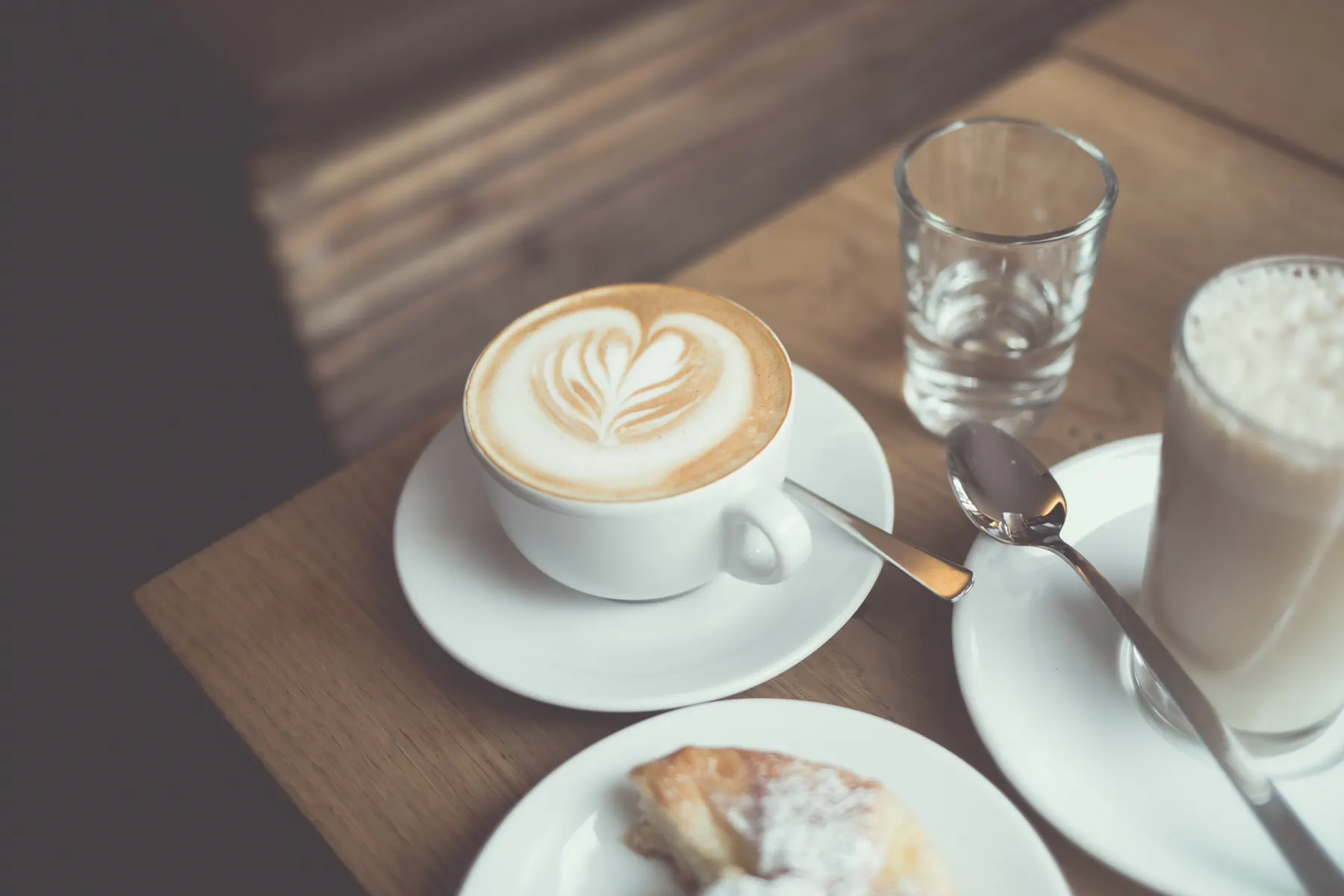 Latte with leaf art in a white cup on a wooden table