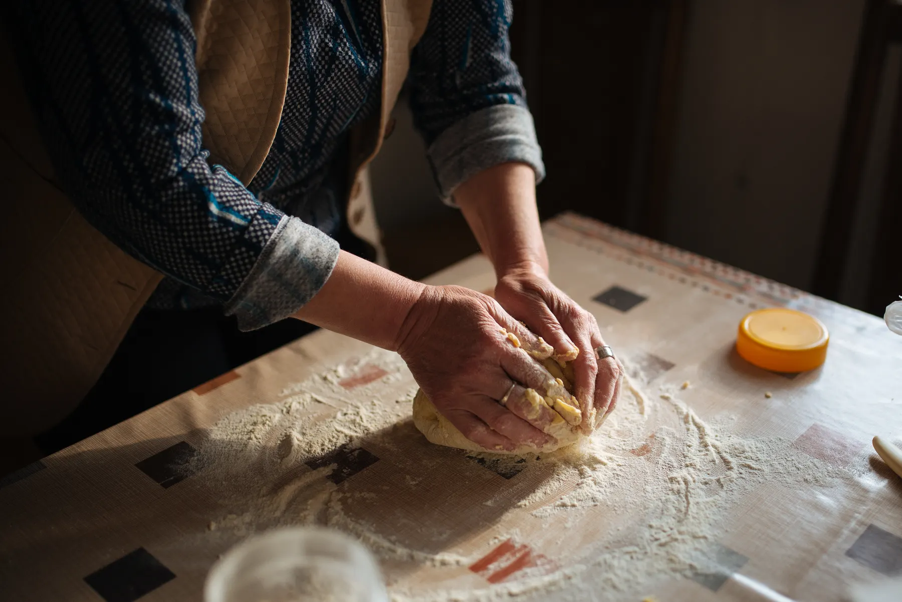 Hands kneading bread dough on a floured counter