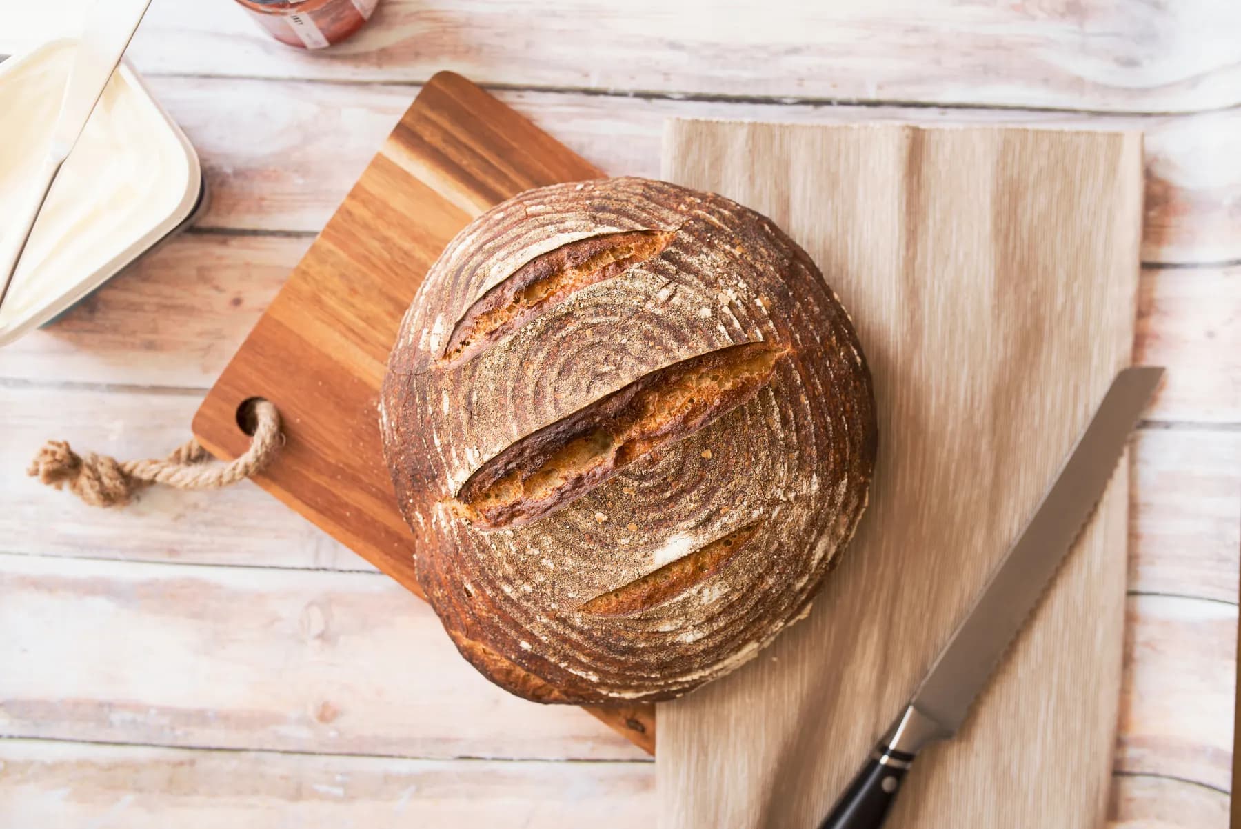 Round sourdough loaf with a scored crust resting on a wooden board